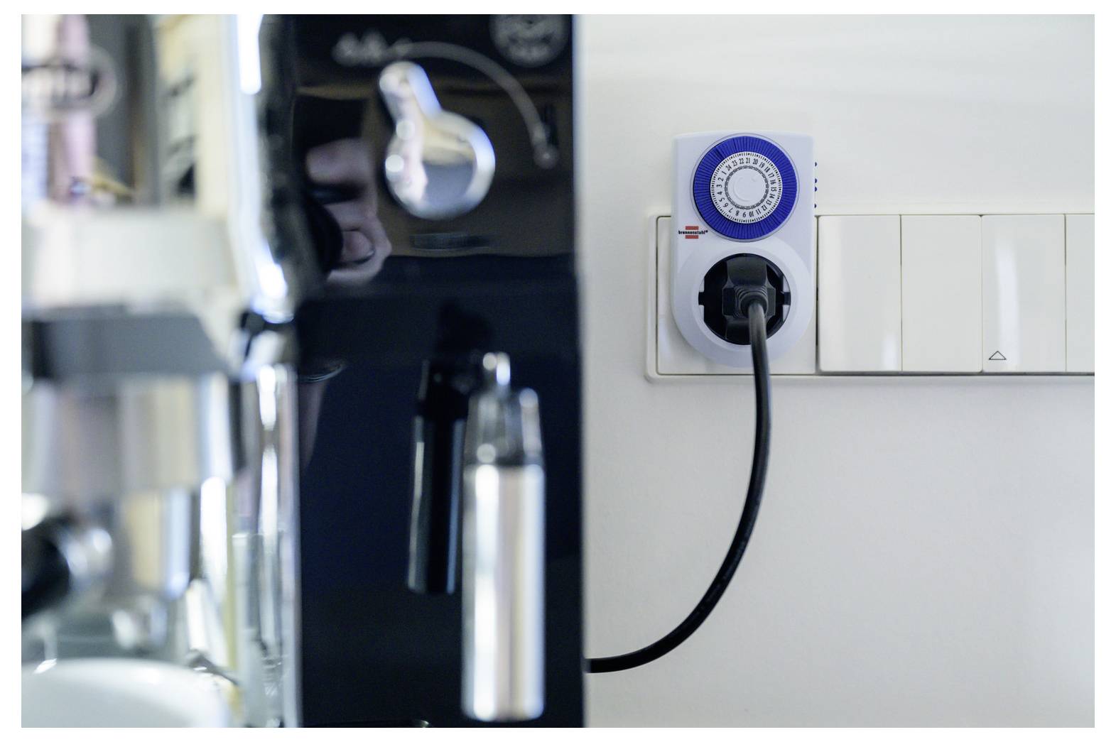 Elektrische Kaffeemaschine, die in eine Wandsteckdose mit Zeitschaltuhr in einer Küche eingesteckt ist, zeigt geplante Stromversorgungskontrolle an.
