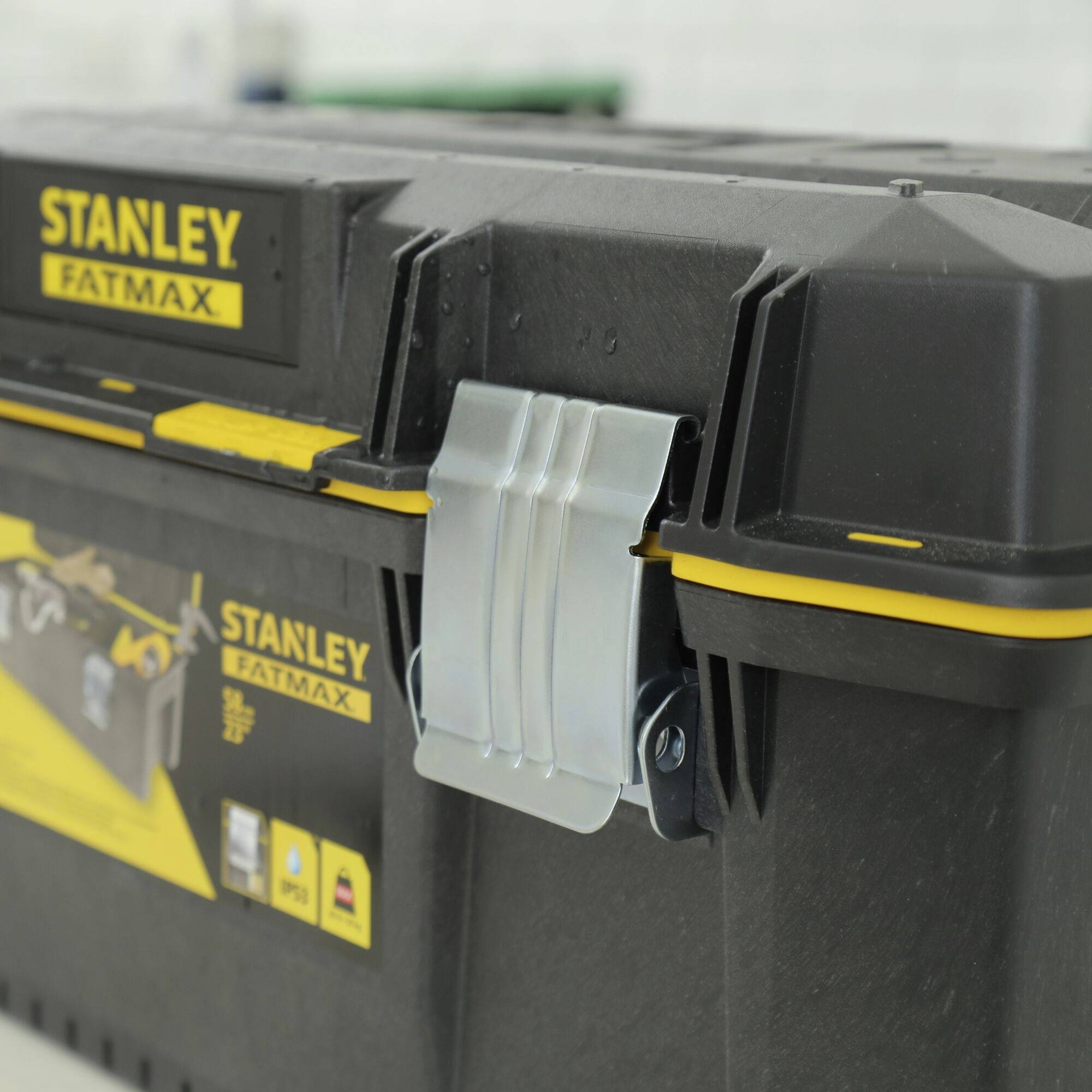 Werkzeugkiste aus schwarzem Kunststoff mit gelbem 'Stanley Fatmax'-Logo. Schließt mit einem silbernen Metallscharnier.