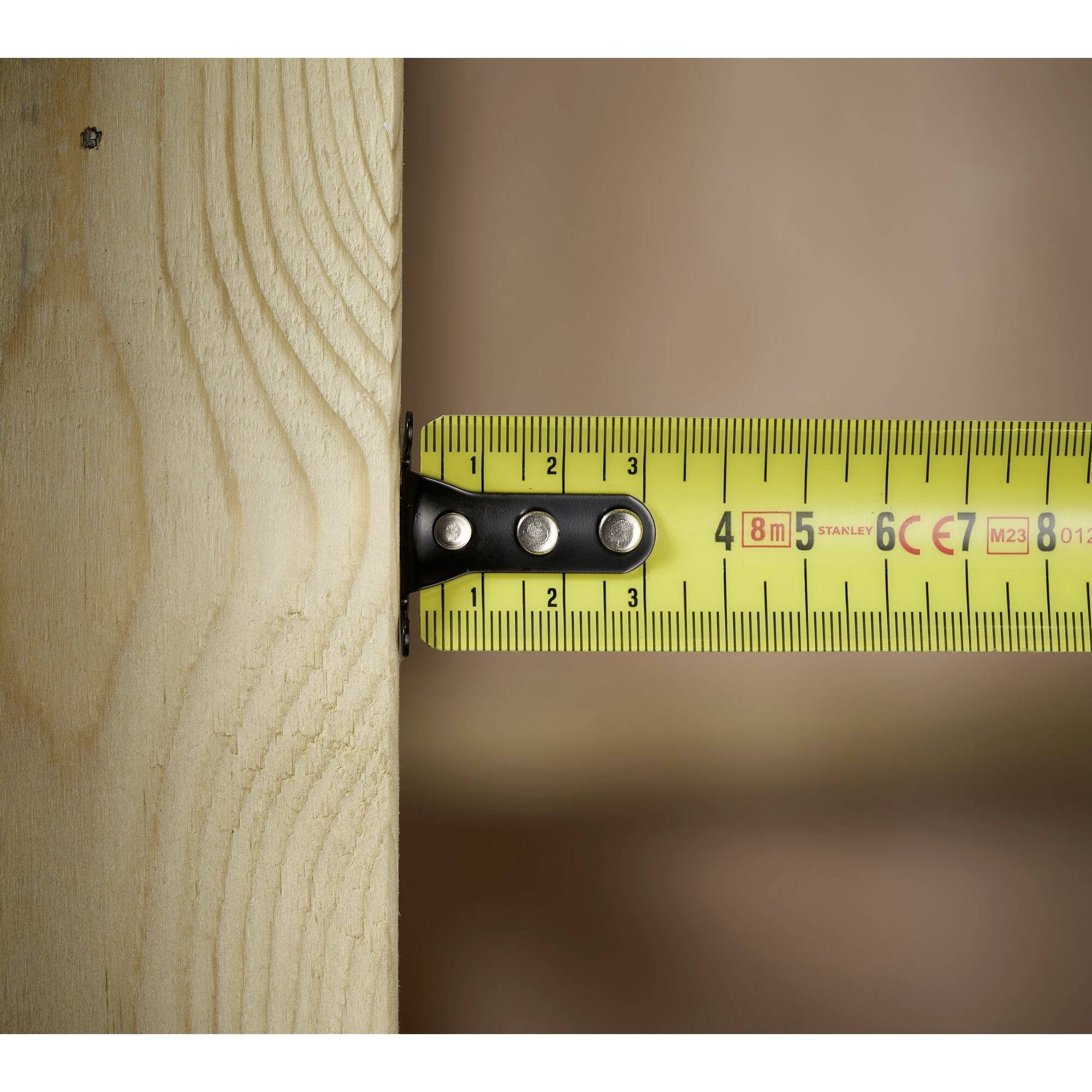 Ein gelbes Maßband misst die Breite eines Holzbretts, das etwa 4,8 cm breit ist. Das Brett hat eine sichtbare Maserung.