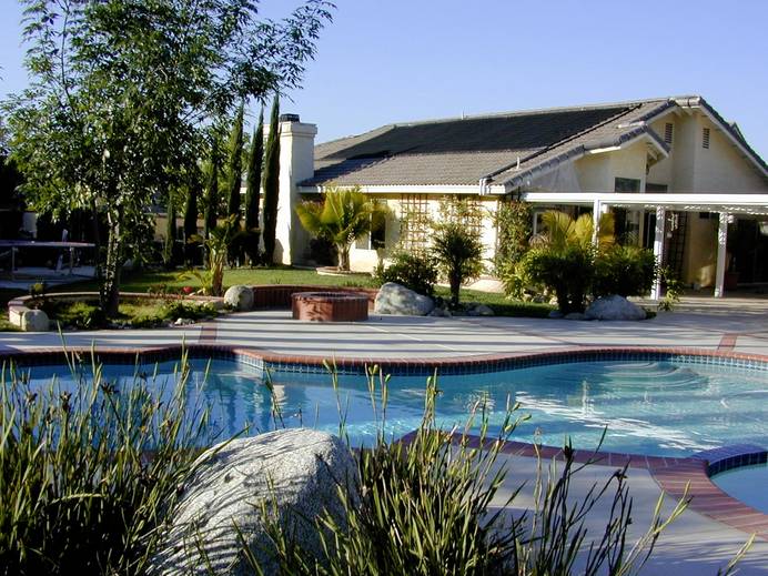 Anwesen mit Pool. Im Hintergrund ist das Haus zu sehen, dessen Dach mit Solarmodulen ausgestattet ist.