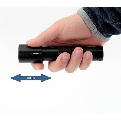 Hand hält eine schwarze Taschenlampe; Pfeil darunter zeigt Fokusverstellung, Hinweis 'FOCUS' zeigt Richtung.