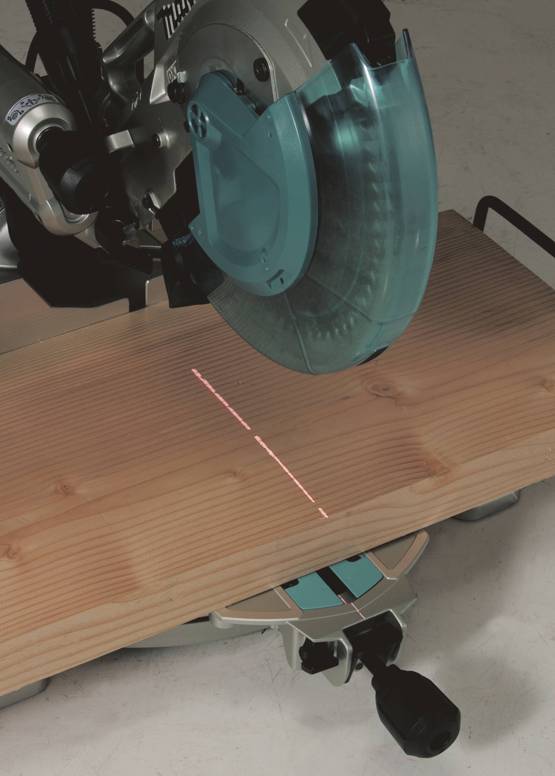 Eine elektrische Gehrungssäge mit Schutzabdeckung schneidet ein Holzbrett. Ein roter Laser zeigt die Schnittlinie an.