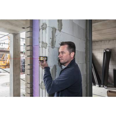 Ein Mann verwendet ein Laser-Entfernungsmessgerät, um die Breite einer Mauer in einem unfertigen Gebäude zu messen.
