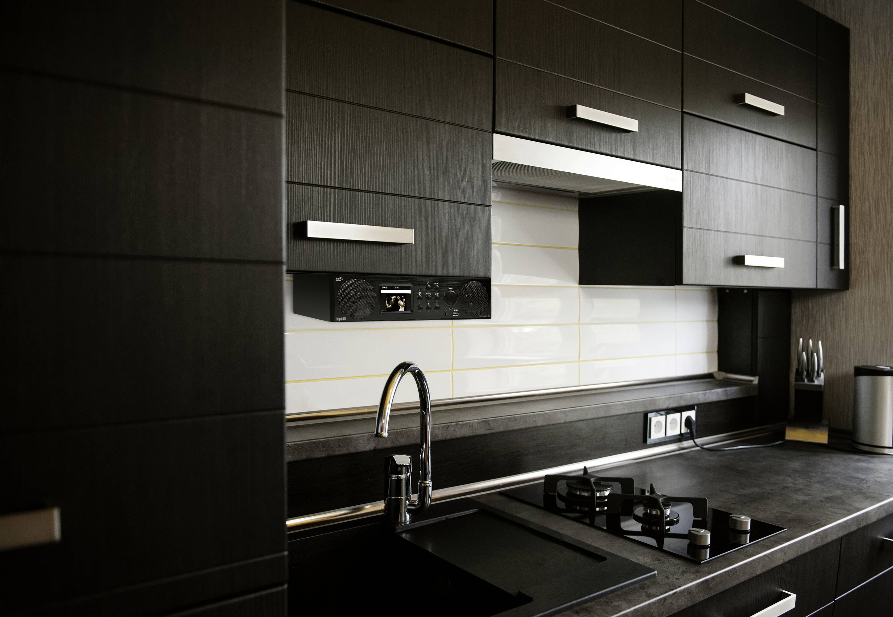 Moderne Küche mit schwarzen Schränken, Gasherd und Spüle aus Edelstahl. Helle Fliesenrückwand und dunkle Arbeitsplatte.