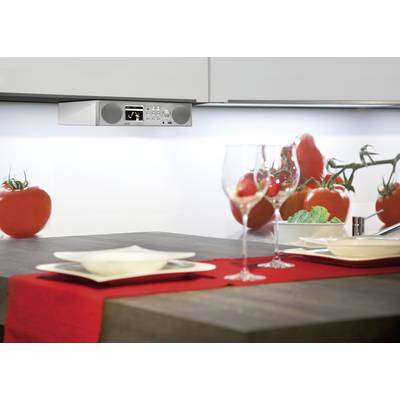 Küchentisch mit rotem Läufer, gedeckt für zwei. Tomaten im Hintergrund; an der Wand ein Radio mit Display und Lautsprechern.