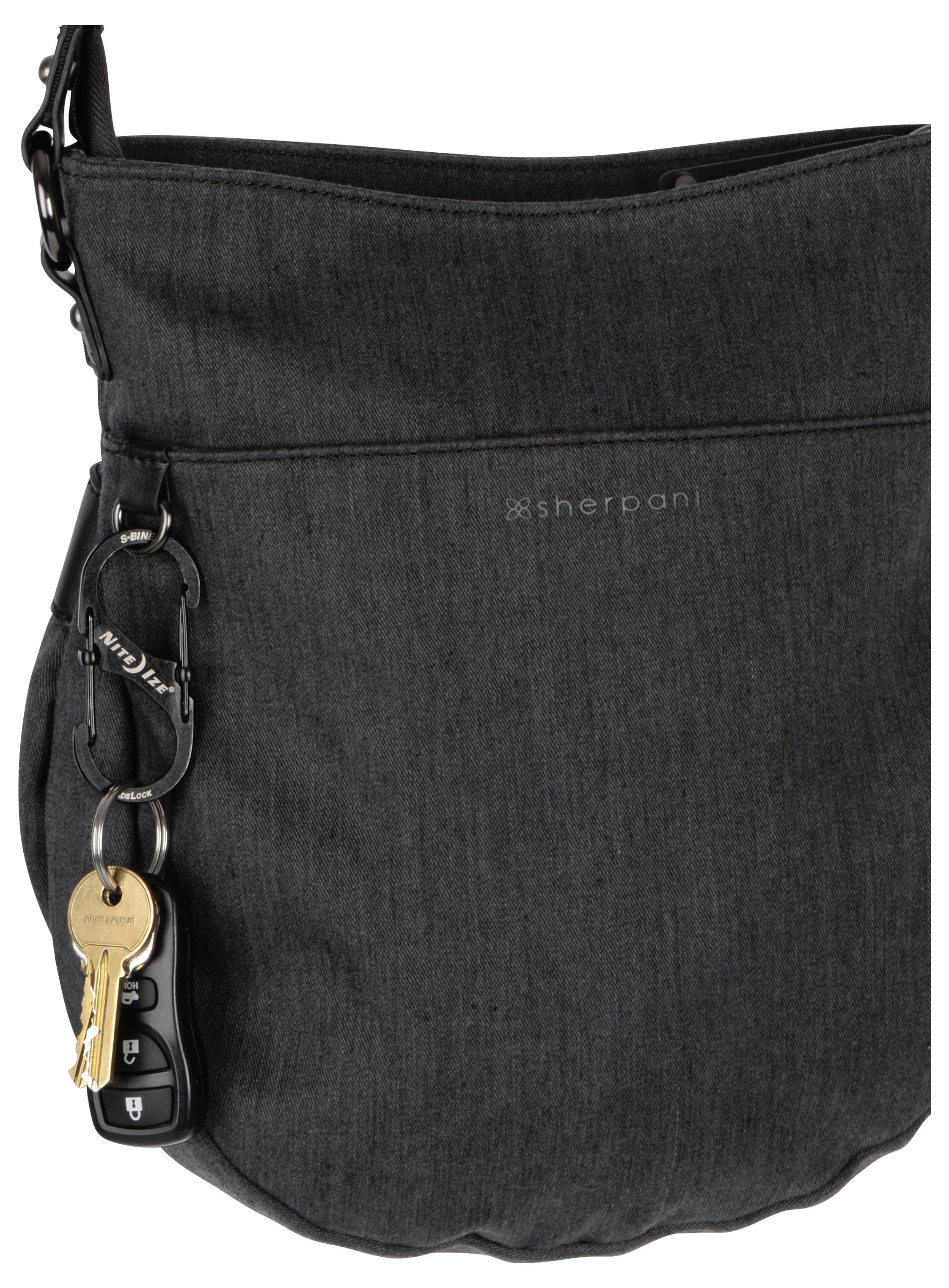 Eine dunkelgraue Umhängetasche mit einem Autoschlüssel, der an einer Schlaufe an der Seite befestigt ist. Der Markenname ist in dezenten Buchstaben auf der Vorderseite eingestickt.