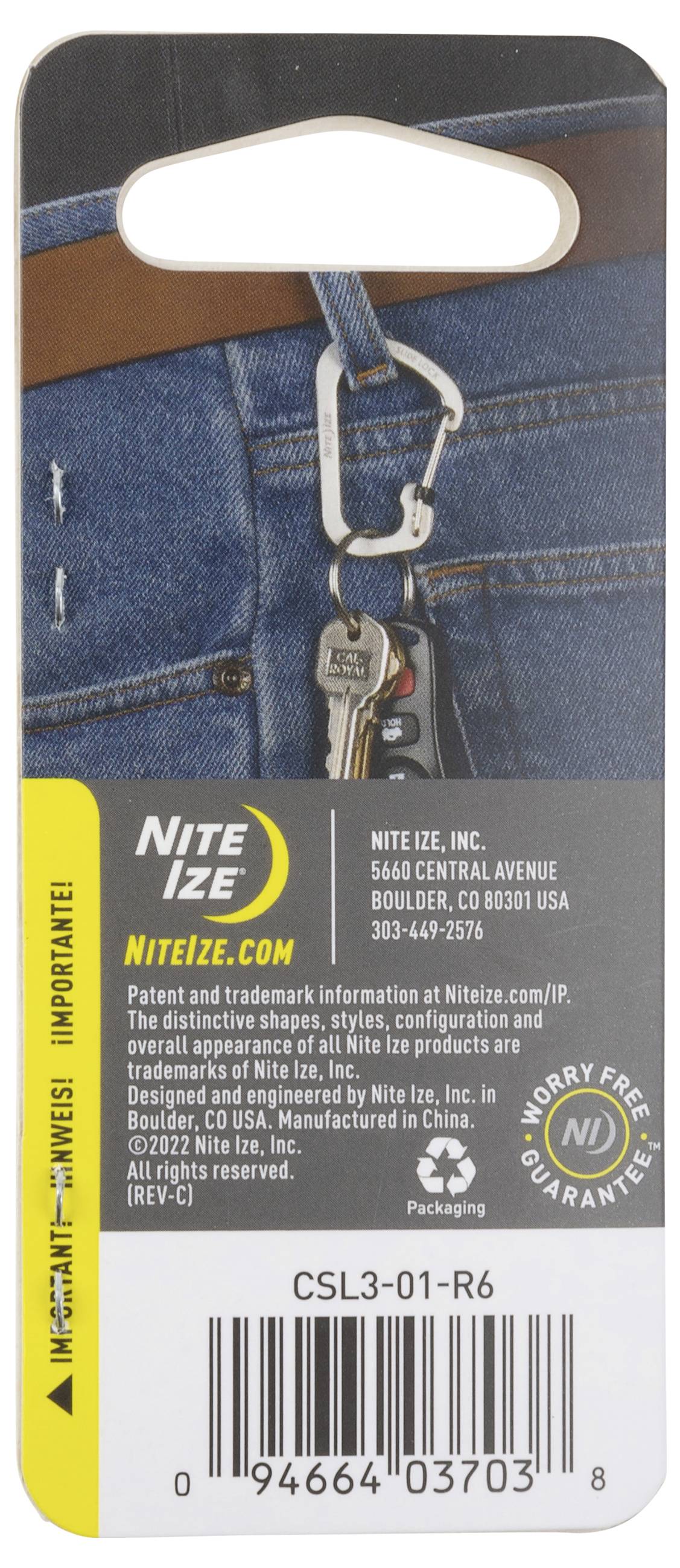 Ein Schlüsselclip, der an einer Gürtelschlaufe einer Jeans befestigt ist. Die Verpackung zeigt den Produktnamen 'Nite Ize' und die Website 'NITEIZE.COM'.