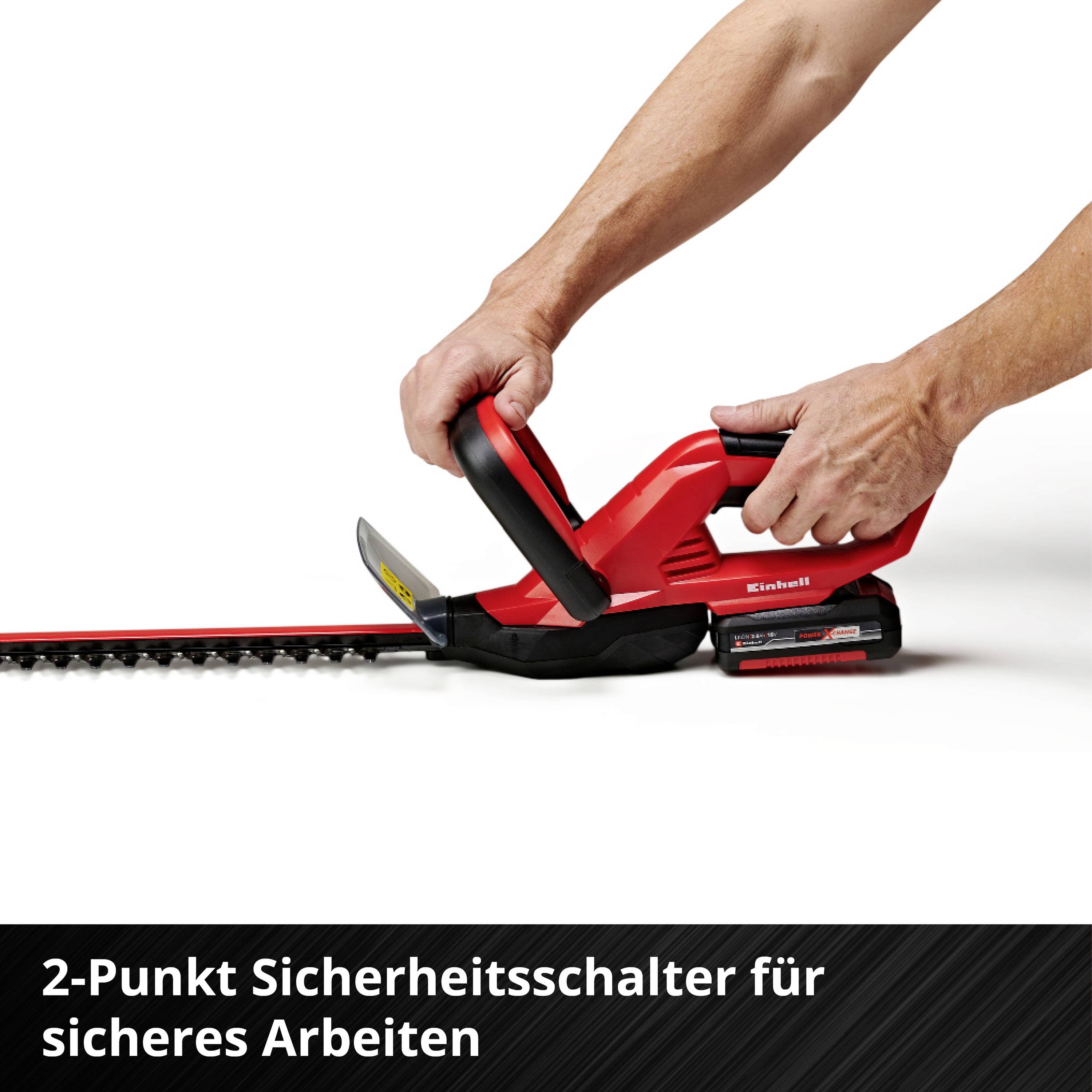 Eine rote Heckenschere mit einem 2-Punkt-Sicherheitsschalter, gehalten von einer Hand. Text unten: '2-Punkt Sicherheitsschalter für sicheres Arbeiten'.