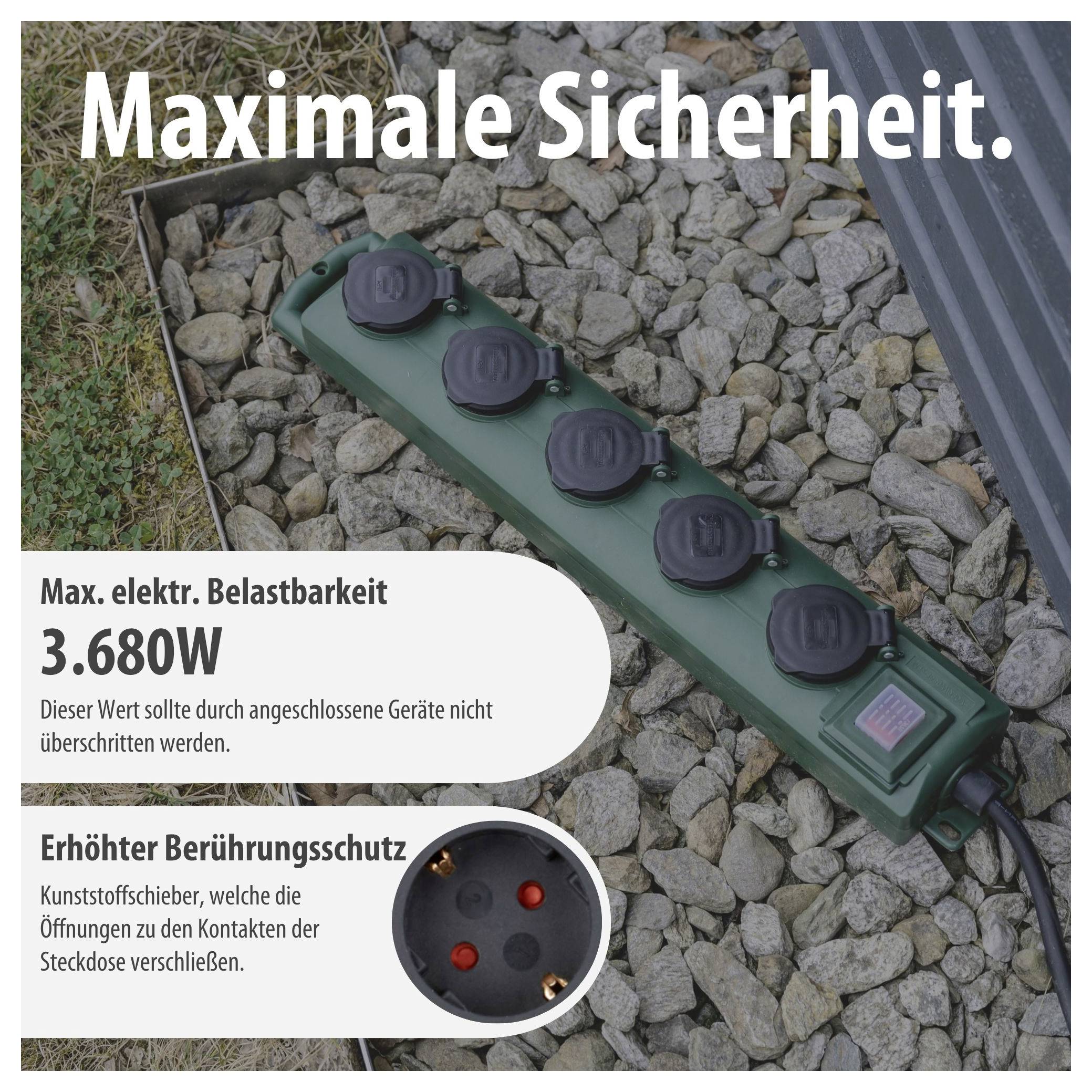 Grüne Außen-Steckdosenleiste auf Kies mit Abdeckung; Text nennt 'Maximale Sicherheit', max. elektrische Belastbarkeit 3.680W und erhöhten Berührungsschutz.