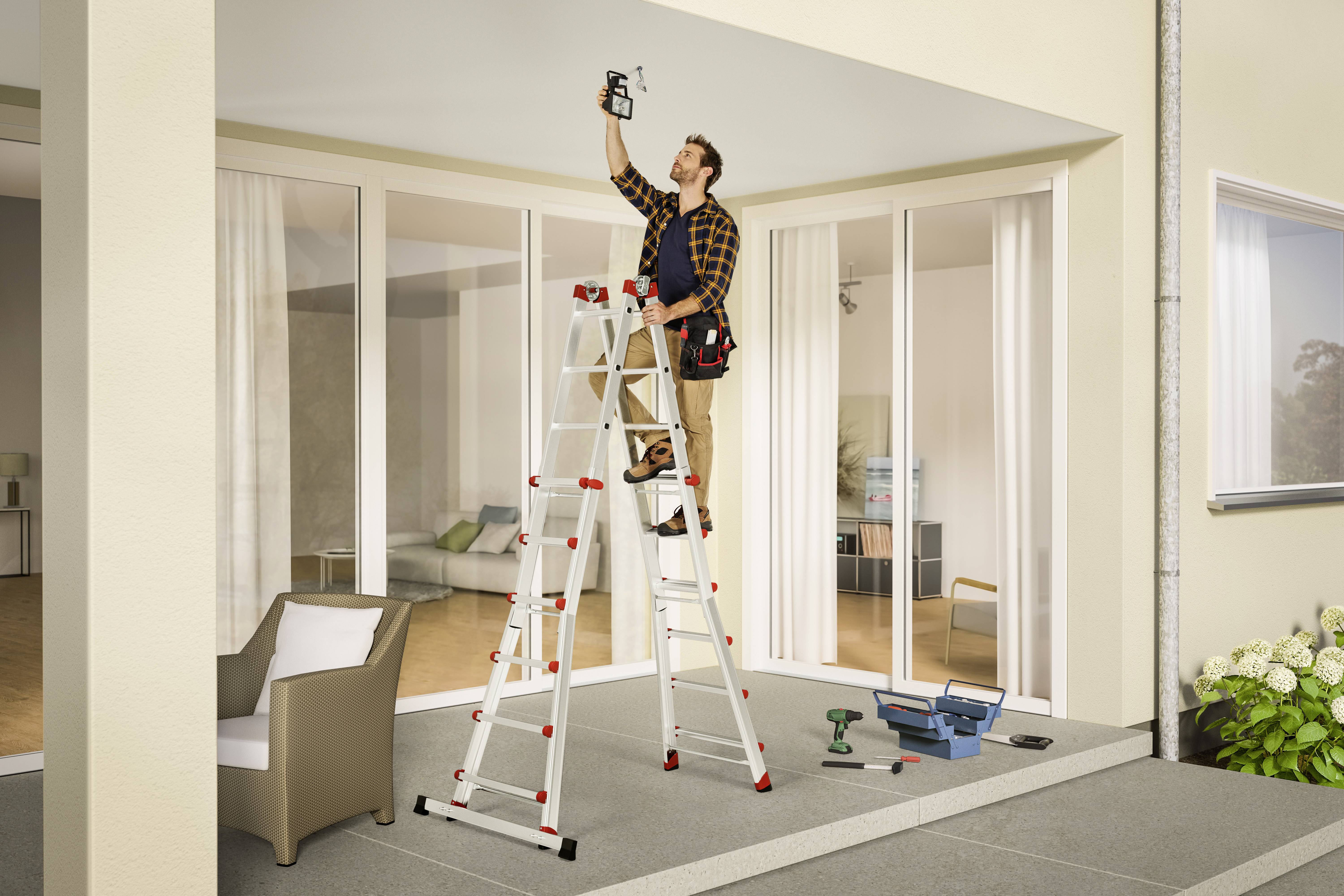 Ein Mann steht auf einer Leiter und bohrt in die Decke einer überdachten Terrasse. Im Hintergrund sind Glasschiebetüren zu sehen.