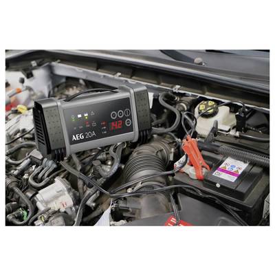 Ein Autobatterieladegerät, das "14,2" anzeigt, ist mit einer Autobatterie im Motorraum eines Fahrzeugs verbunden, wobei Kabel an den Batterieanschlüssen befestigt sind.
