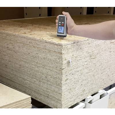 Ein Stapel Holzplatten wird mit einem Feuchtigkeitsmessgerät überprüft. Das Gerät zeigt 7,9 Prozent Feuchtigkeit an.