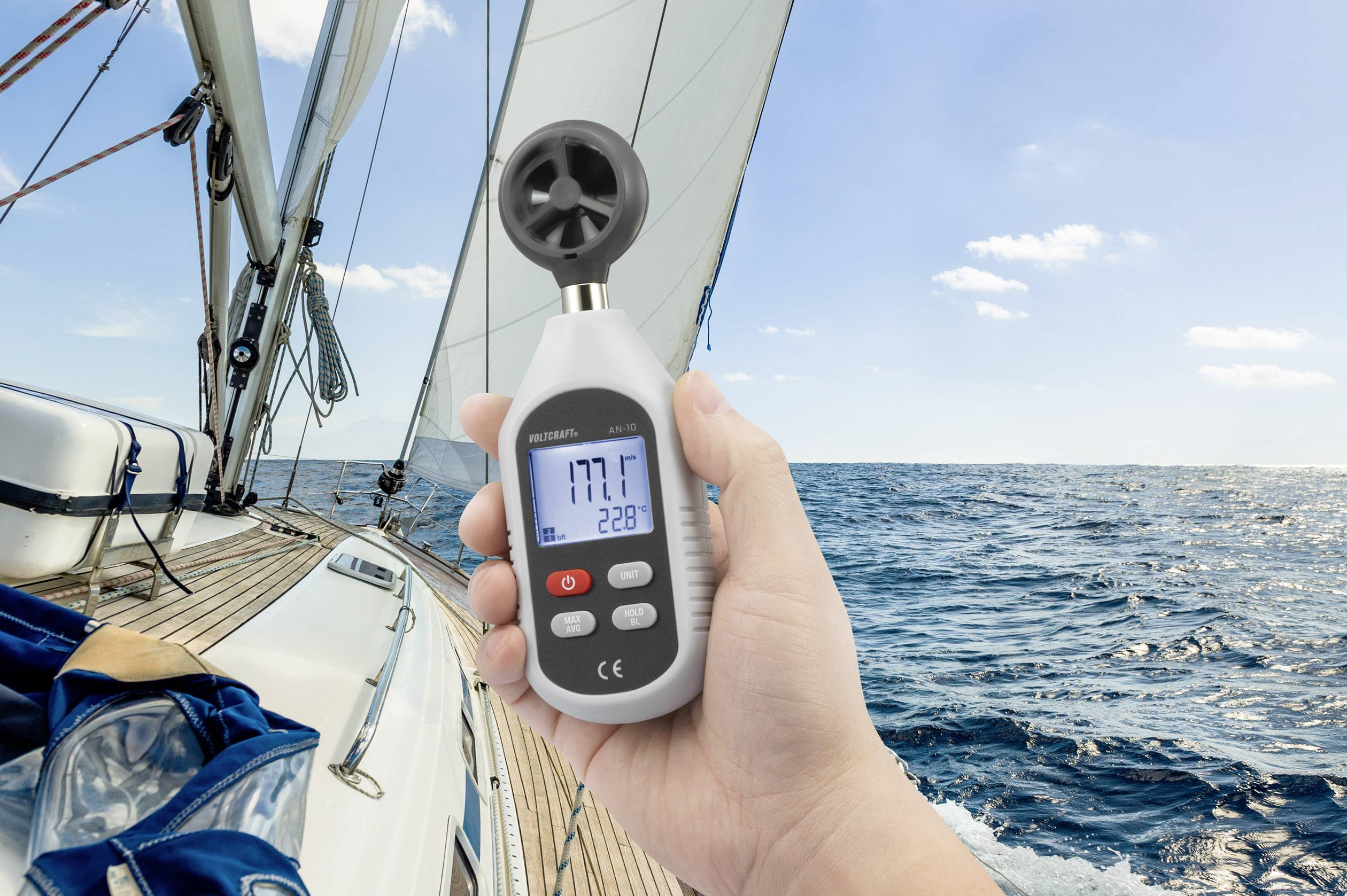Person hält ein Anemometer auf einem Segelboot; das Gerät zeigt '17.7' Knoten Windgeschwindigkeit bei klarem Himmel.