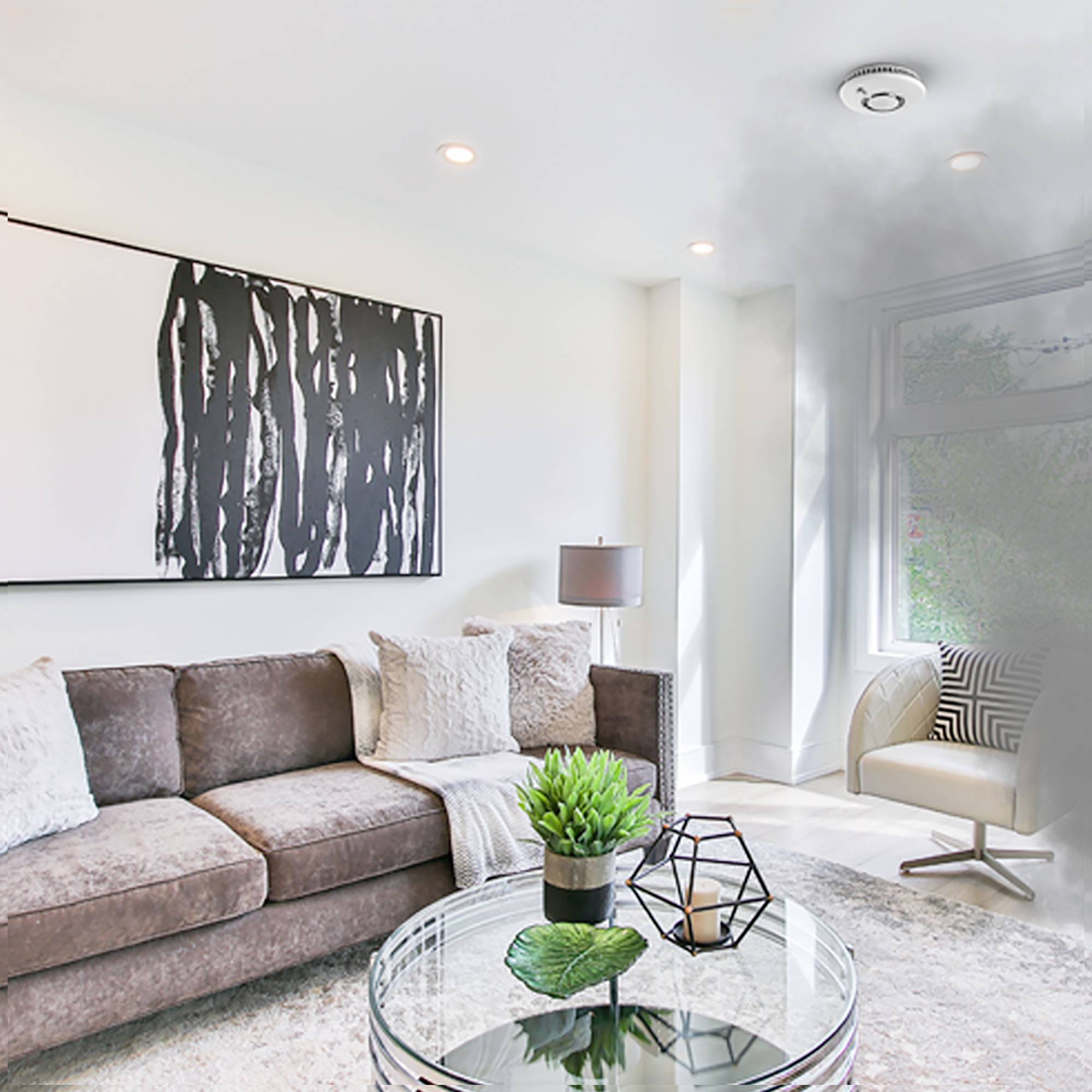 Ein moderner Wohnraum mit einem braunen Sofa, einem Glastisch, abstrakter Kunst an der Wand und viel natürlichem Licht durch ein großes Fenster.