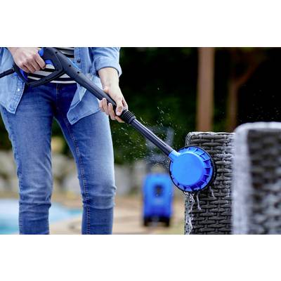 Eine Person reinigt einen Gartenstuhl mit einem Hochdruckreiniger. Wasser spritzt von der blauen Bürste auf den Stuhl.