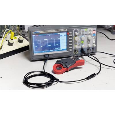Ein Oszilloskop zeigt ein wellenförmiges Signal auf dem Bildschirm. Auf dem Tisch befinden sich elektronische Messgeräte und Kabel.
