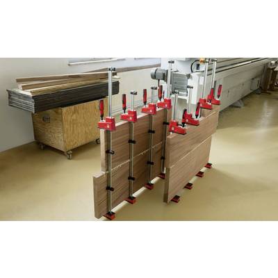 Mehrere Holzplatten werden mit Schraubzwingen zusammengepresst in einer Werkstatt, um eine gleichmäßige Verbindung sicherzustellen.
