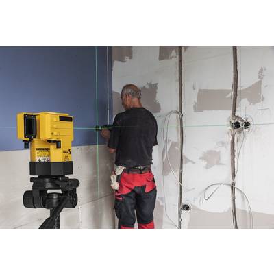Eine Person arbeitet in einem Raum mit unfertigen Wänden, verwendet einen gelben Laser, um Linien zu projizieren, möglicherweise für Bauarbeiten.