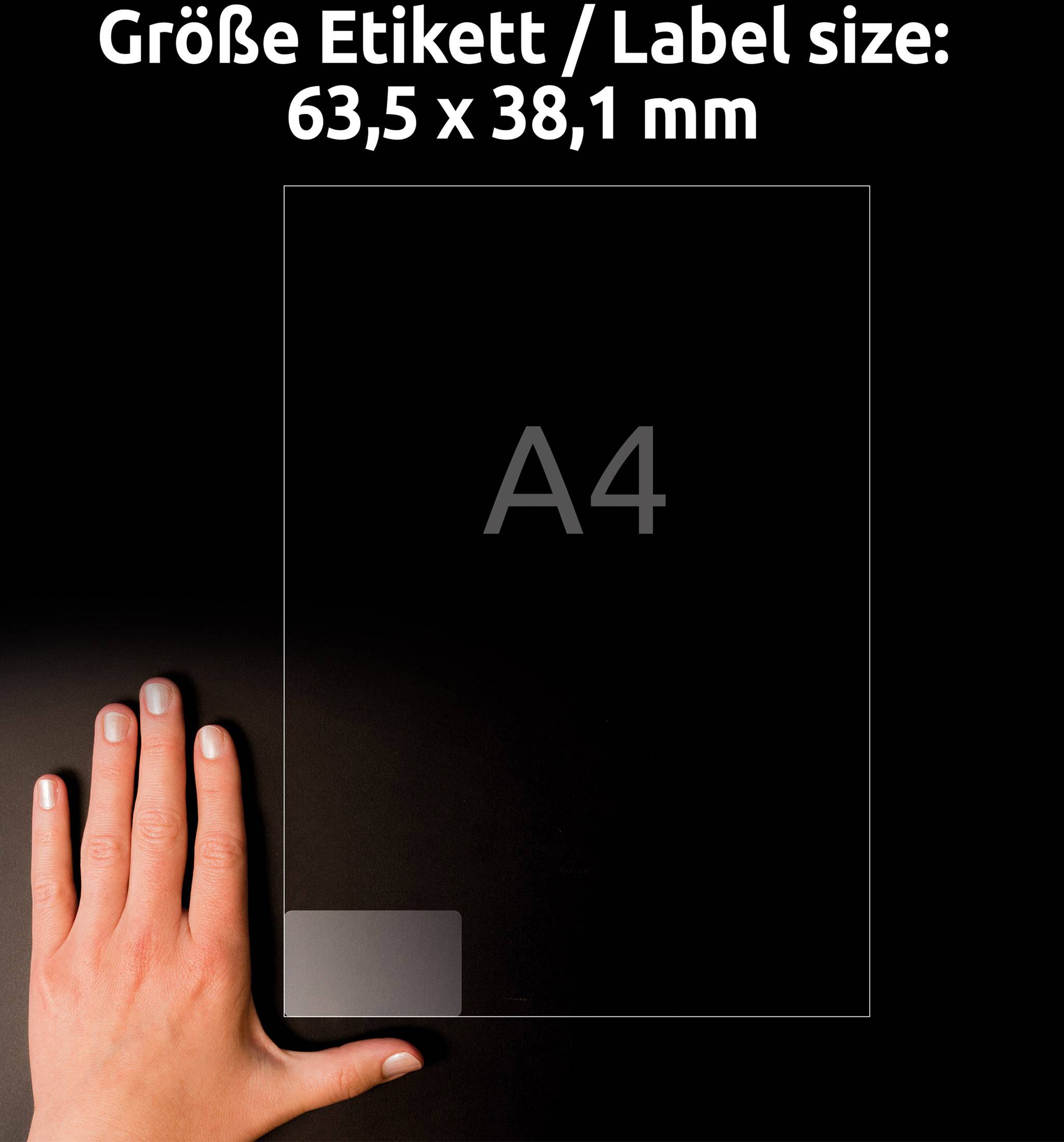 Hand neben einem transparenten Blatt im A4-Format; Etikettengröße 63,5 x 38,1 mm auf schwarzem Hintergrund.