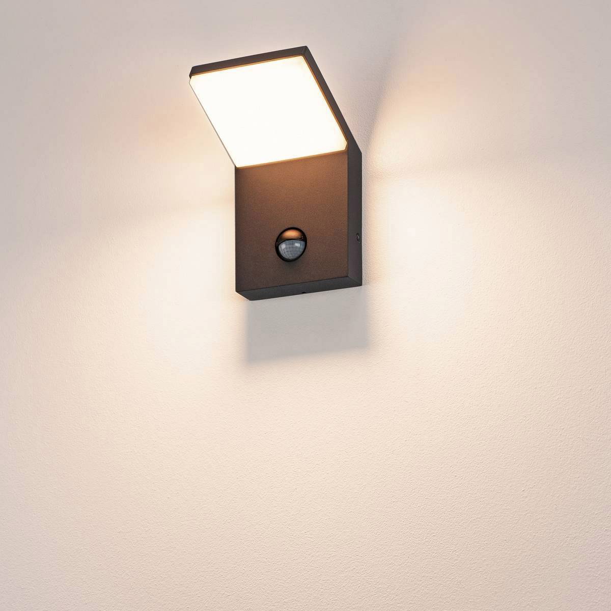 Wandmontierte Außenleuchte mit Bewegungssensor, die ein warmes Licht nach unten abstrahlt.