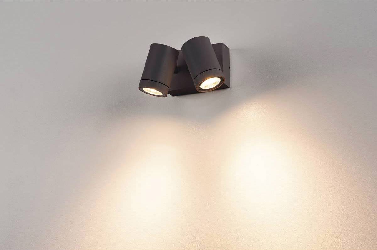 Eine moderne, zweifache Wandlampe beleuchtet die Wand mit warmem Licht, erzeugt einen sanften und einladenden Schein.