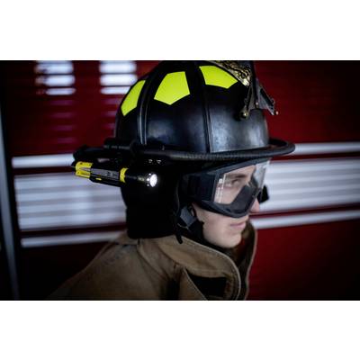 Ein Feuerwehrmann im Profil trägt einen Helm mit integrierter Lampe, Schutzbrille und Schutzanzug vor einem roten Hintergrund.