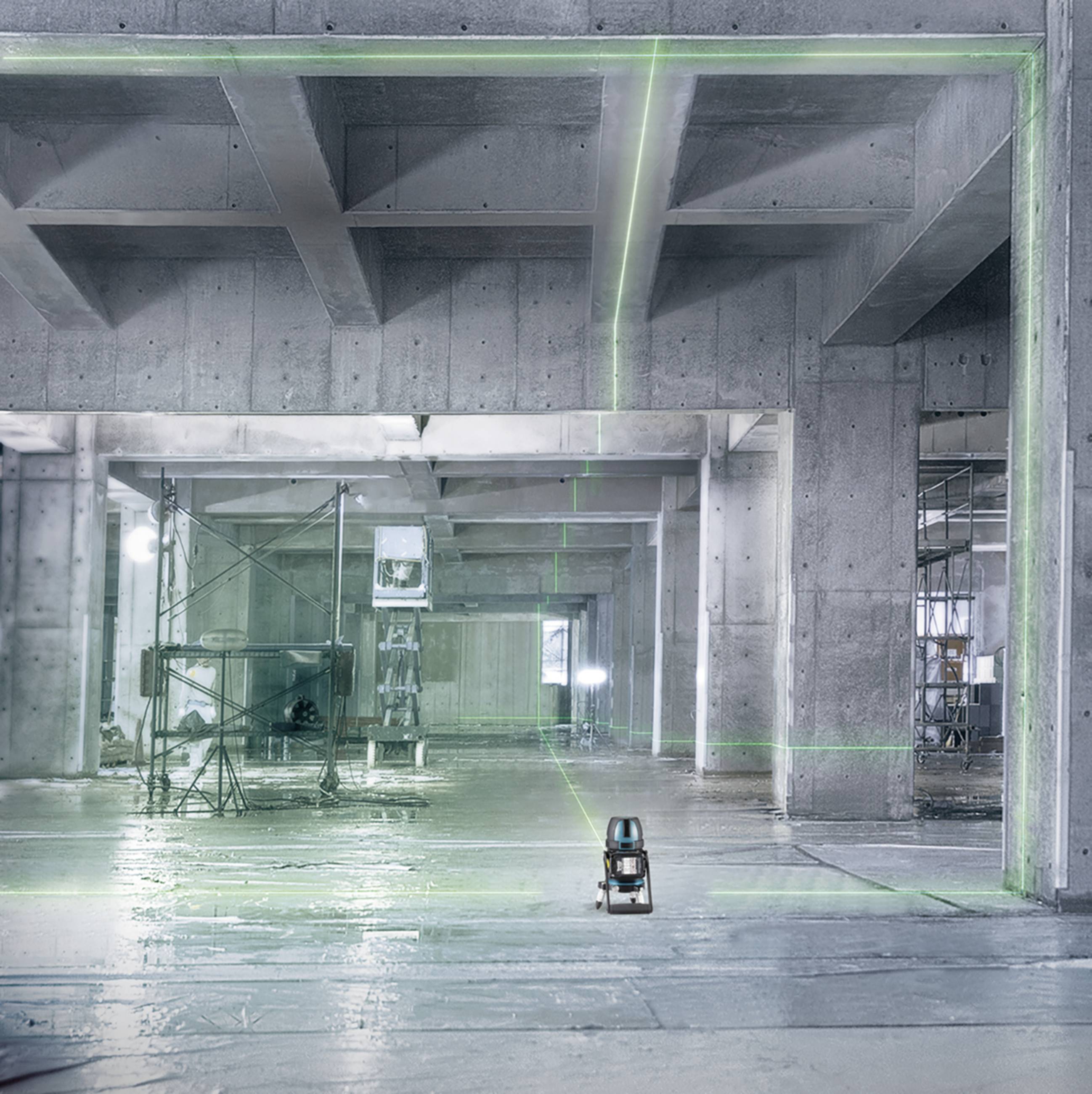 Ein leerer Betonbau mit stählernen Gerüsten und grünen Laserlinien, die den Raum vermessen. Eine Vermessungsausrüstung steht zentral.