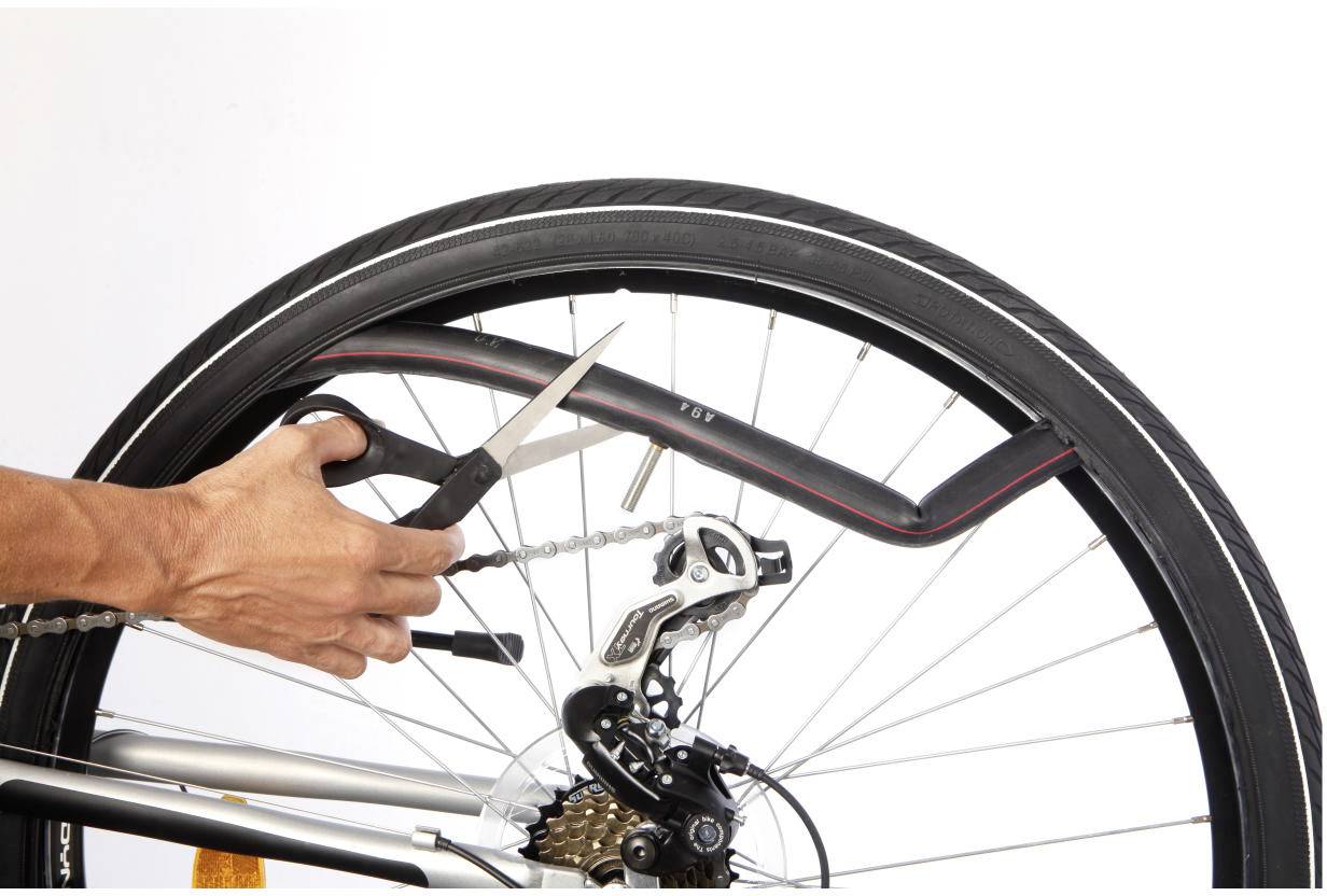 Eine Person schneidet mit einer Schere einen Fahrradreifen auf, um einen platten Schlauch zu reparieren. Der Reifen ist teilweise vom Rad gelöst.