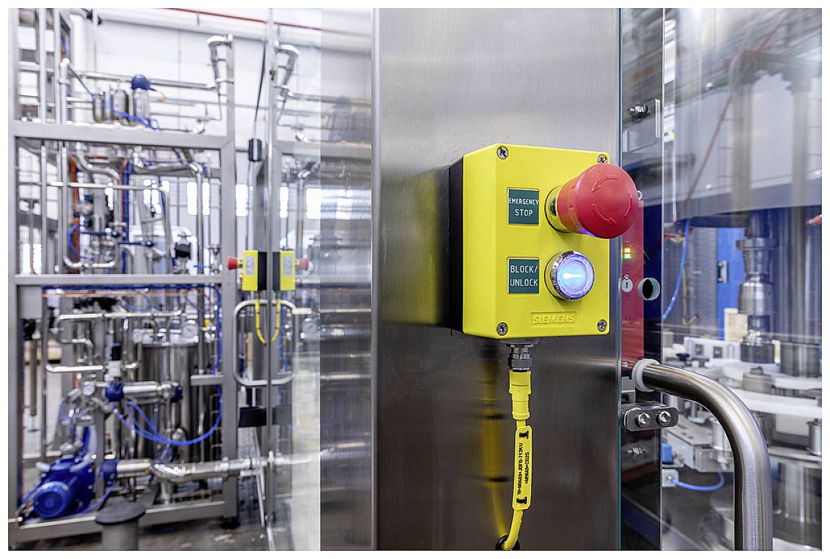 Ein roter Not-Aus-Knopf und ein gelber Kasten mit Knöpfen in einer Industrieanlage zeigen die Sicherheitsvorrichtungen einer Fabrik.