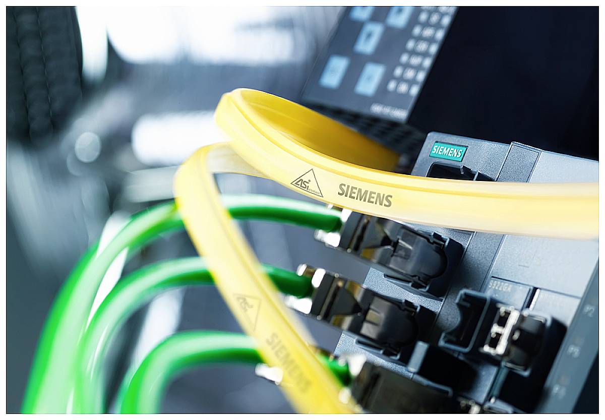 Nahaufnahme von gelben und grünen Kabeln, die an ein Siemens-Gerät angeschlossen sind, in einer technologischen Umgebung.