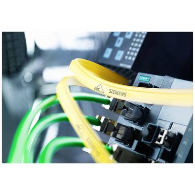Industrieverkabelung mit gelben und grünen Kabeln verbunden an Siemens-Gerät. Im Hintergrund unscharfe technische Anlage.