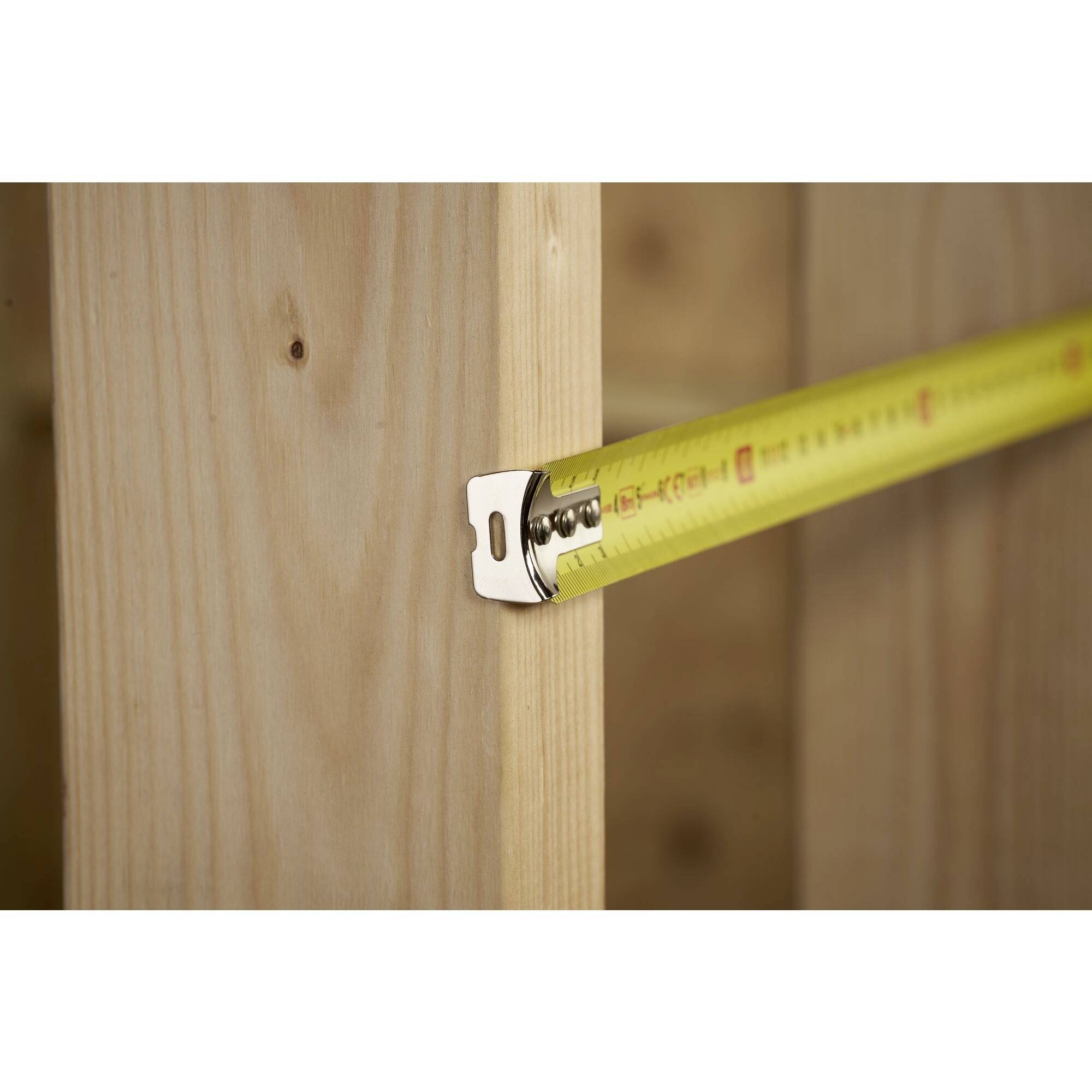 Ein Maßband wird an einem Holzrahmen angelegt, möglicherweise zur Messung beim Bau oder bei Renovierungsarbeiten.