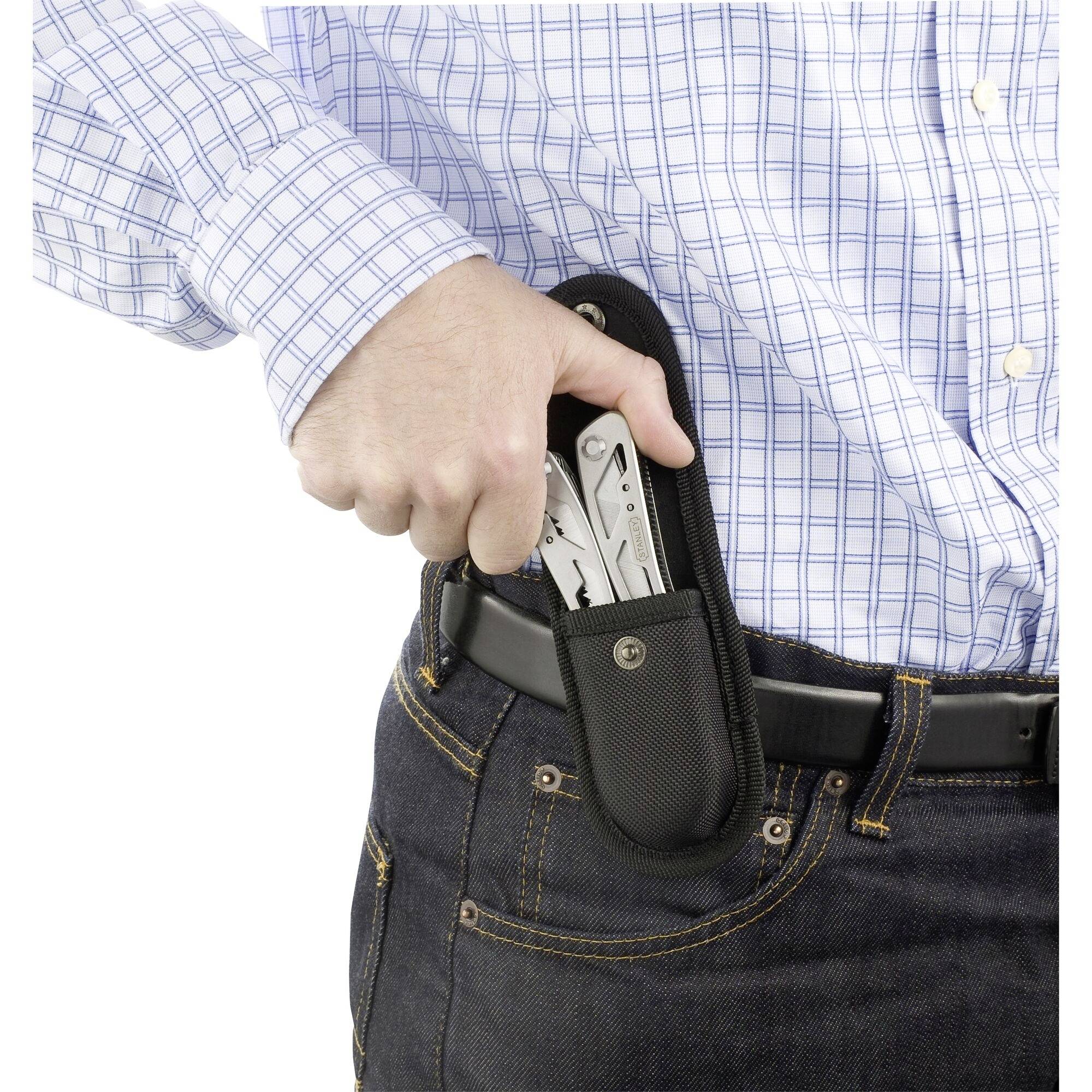 Eine Person steckt ein Multitool in einer schwarzen Tasche in den Gürtel ihrer blauen Jeans. Die Person trägt ein blau-weiß kariertes Hemd.