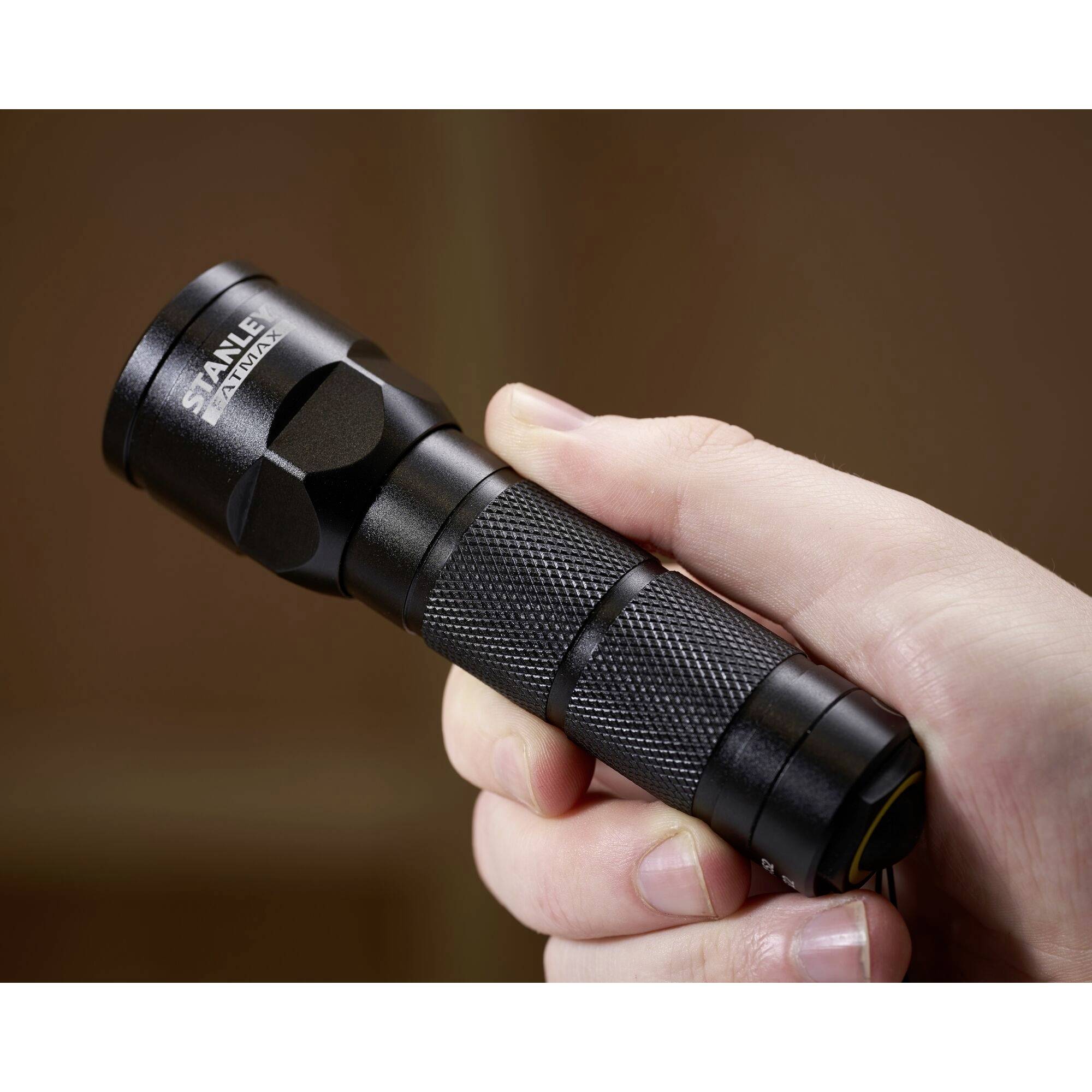 Eine Hand hält eine schwarze Taschenlampe. Sie ist kompakt und wirkt robust, ideal für den Einsatz in dunklen Umgebungen.