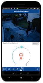 Smartphone zeigt Sicherheitskamera-Aufnahme einer Person im Garten bei Nacht. Darunter App-Interface zur Kontrolle der Beleuchtung.