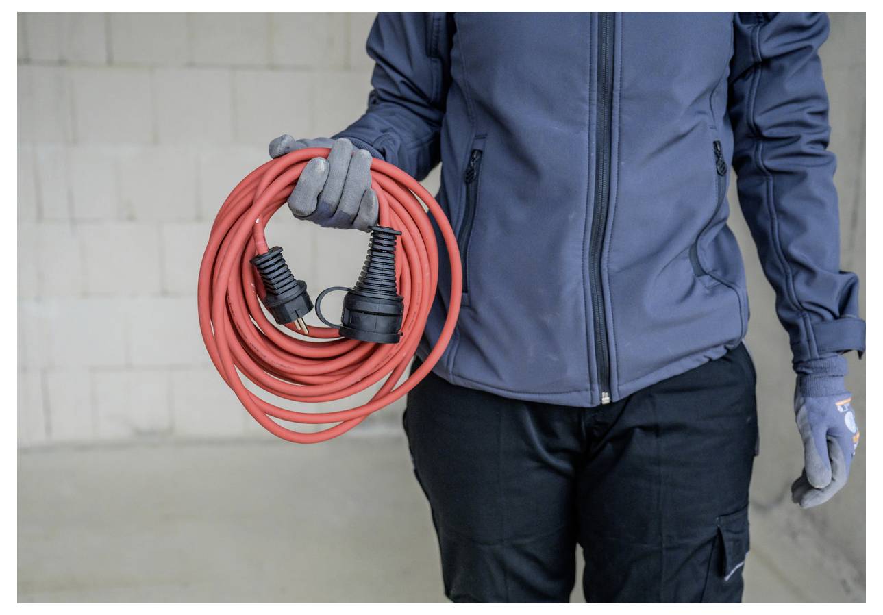 Person in Arbeitskleidung, die ein aufgerolltes rotes Verlängerungskabel mit schwarzen Steckern hält.
