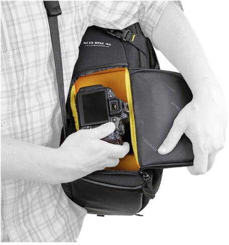 Person öffnet eine Kameratasche und nimmt eine Kamera heraus. Die Tasche ist schwarz mit orangem Innenfutter.