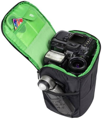 Schwarze Kameratasche mit grünem Inneren, offen mit einer Kamera, Blitz, Objektiv und Speicherkarten. Ideal für Fotografie unterwegs.