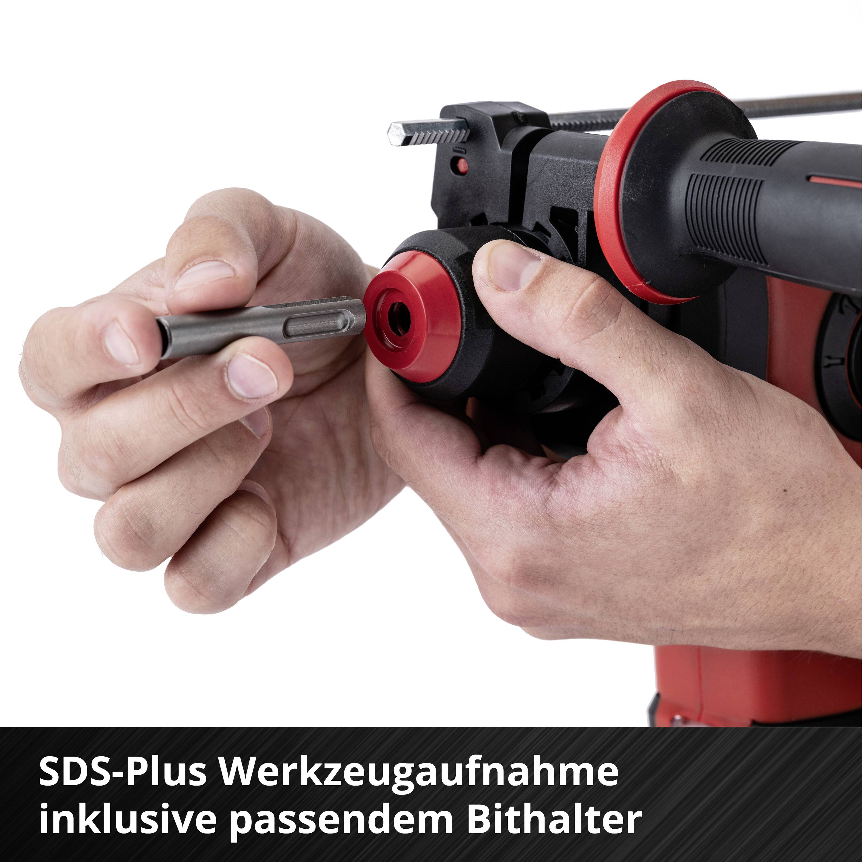 Ein roter Bohrhammer wird mit einem SDS-Plus Werkzeug eingesetzt. Eine Hand hält den Bohrer, während die andere den Bohrhammer stabilisiert.