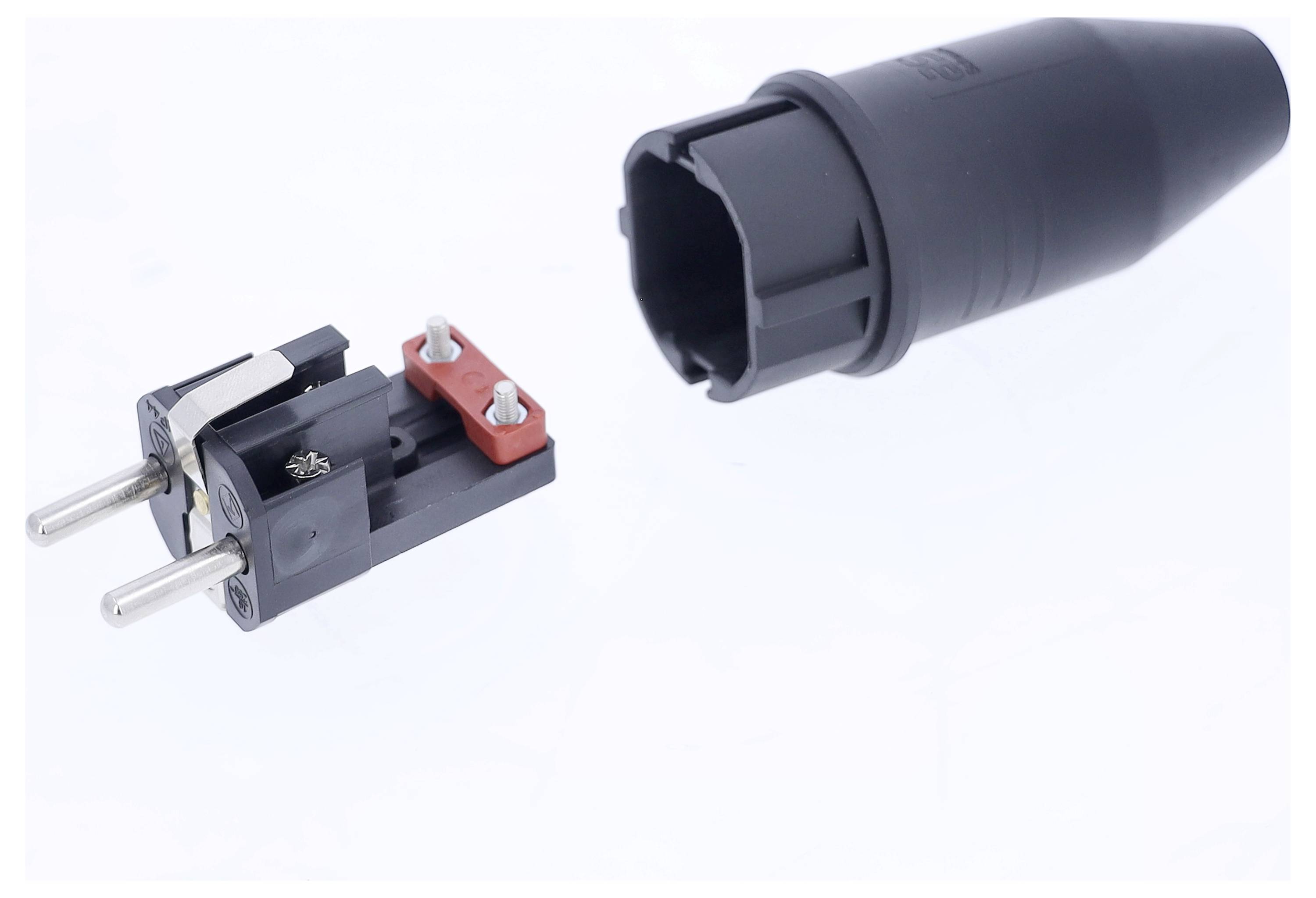 Abgebildet ist ein zerlegter elektrischer Stecker mit zwei Metallstiften und einer schwarzen Kunststoffabdeckung.