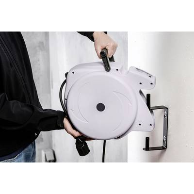 Eine Person montiert eine graue automatische Kabeltrommel an eine Wandhalterung.