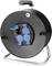 Eine schwarze Kabeltrommel mit drei blauen Steckdosen und rotem Schalter, montiert auf einem Metallrahmen mit Griff.