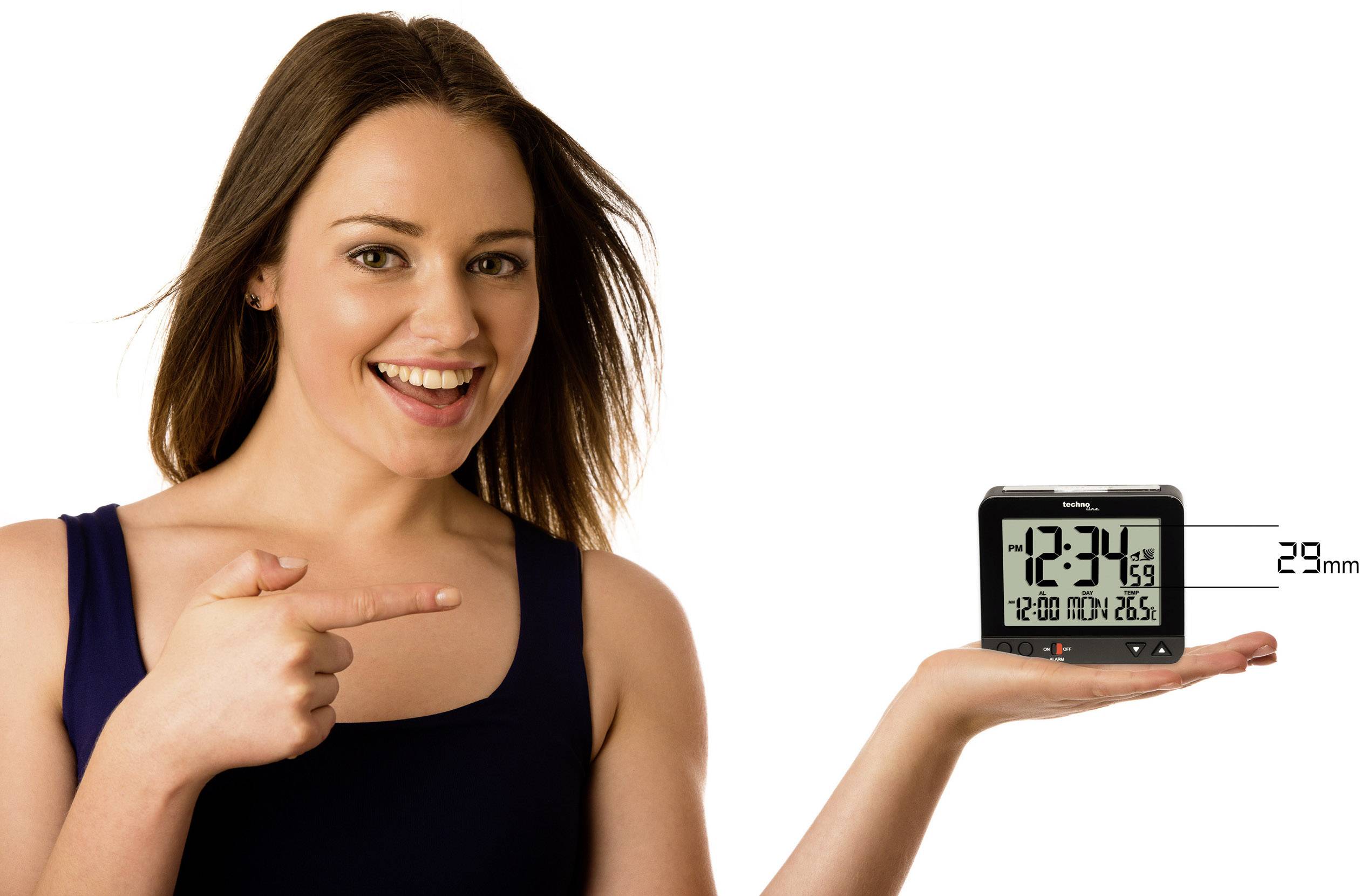 Frau zeigt auf digitalen Wecker, der Zeit '12:34', Datum 'Freitag, 25.06.' und Wetter '29mm Regen' anzeigt.