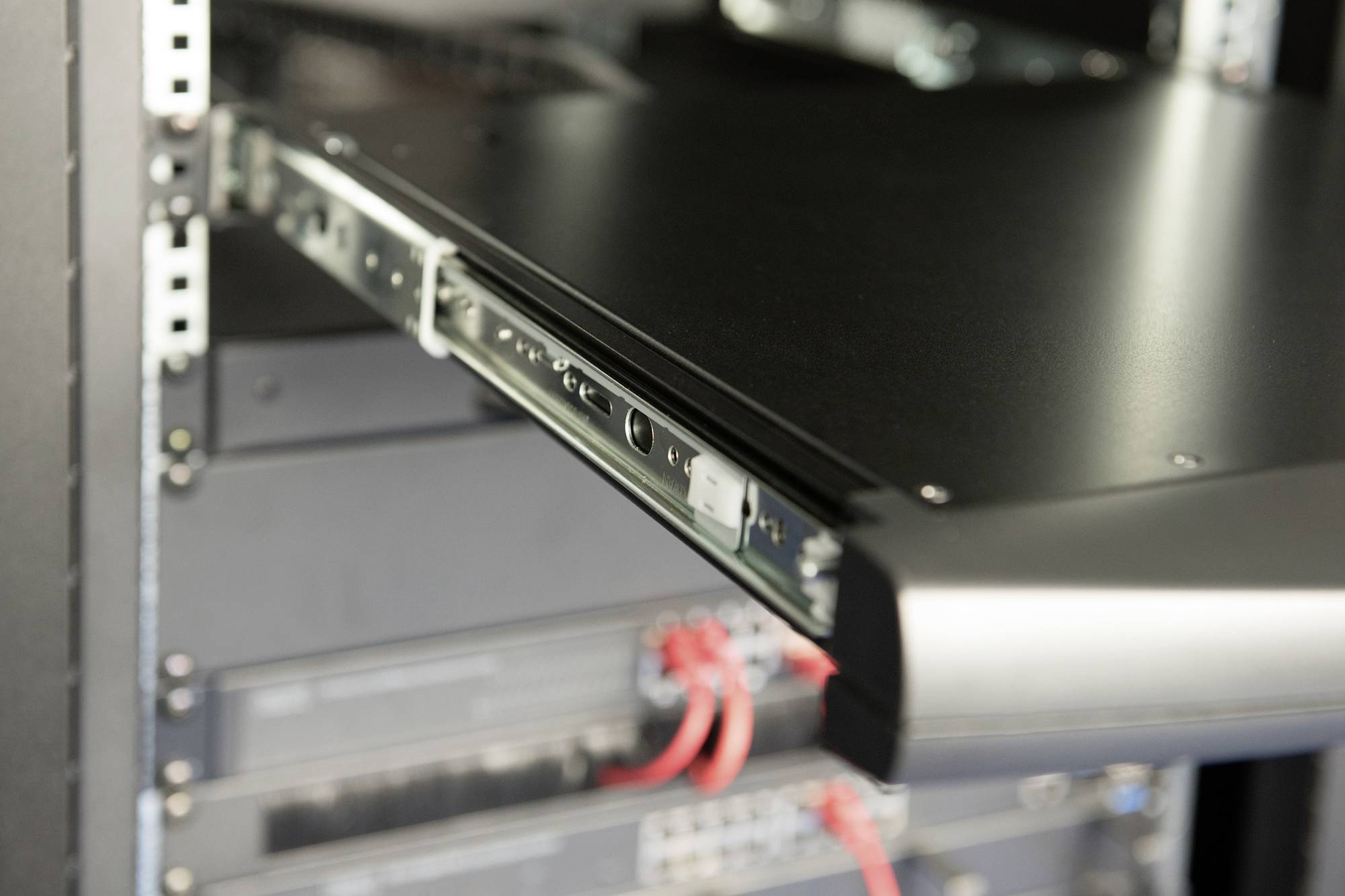 Ein offenes Server-Rack mit einem herausgezogenen Server, umgeben von anderen Servern und erkennbaren Kabelverbindungen.