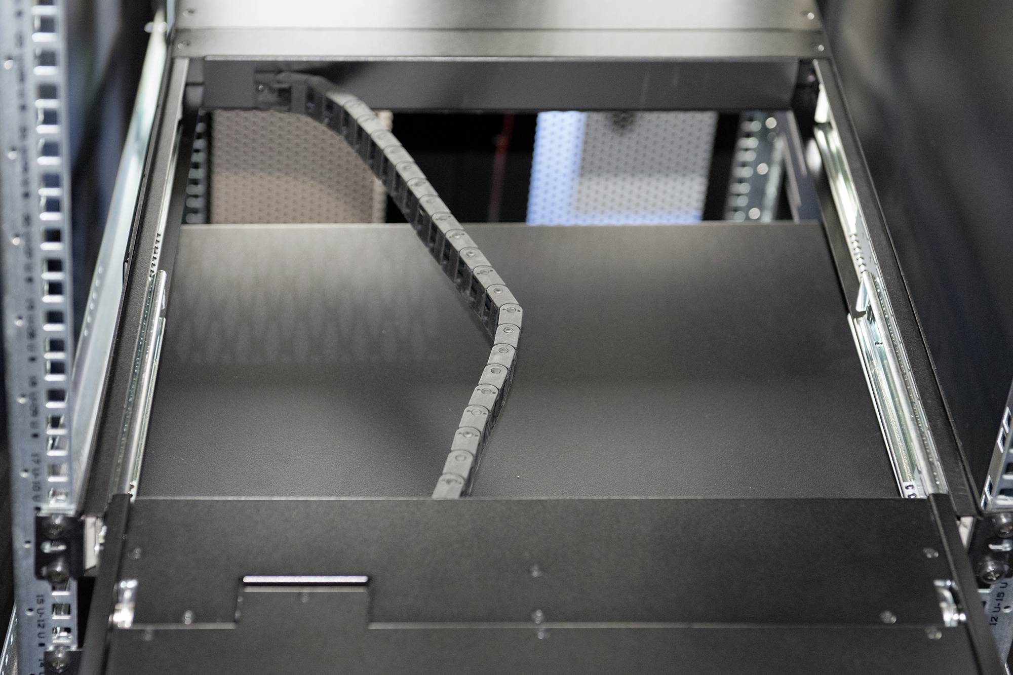 Ein leerer Server-Rack-Schub in einem Rechenzentrum, mit einem flexiblen Kabel, das in den Schub hineinragt.