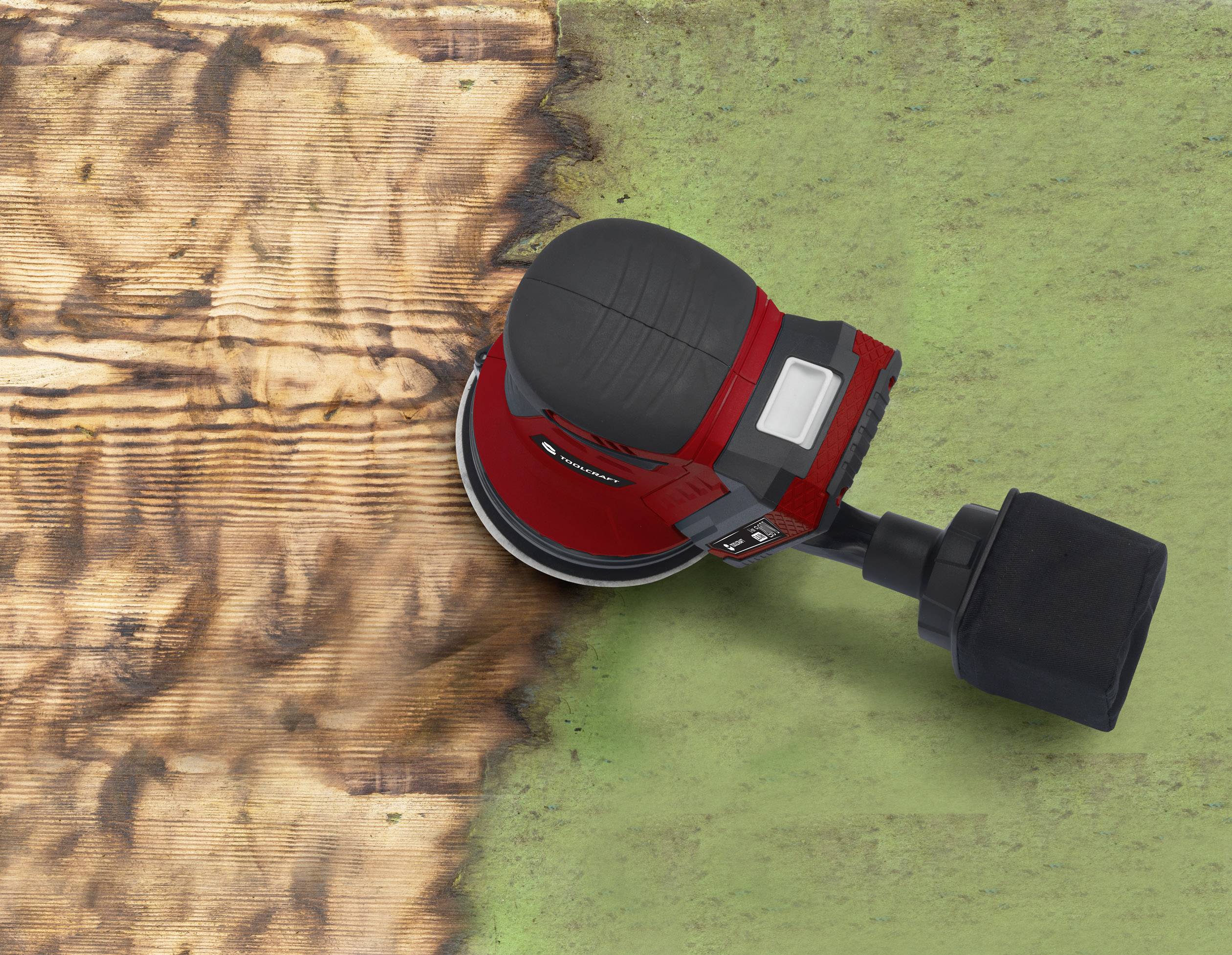 Ein roter Exzenterschleifer schleift ein Holzbretterstück. Links ist das Holz glatt, rechts bleibt die grün lackierte Oberfläche.