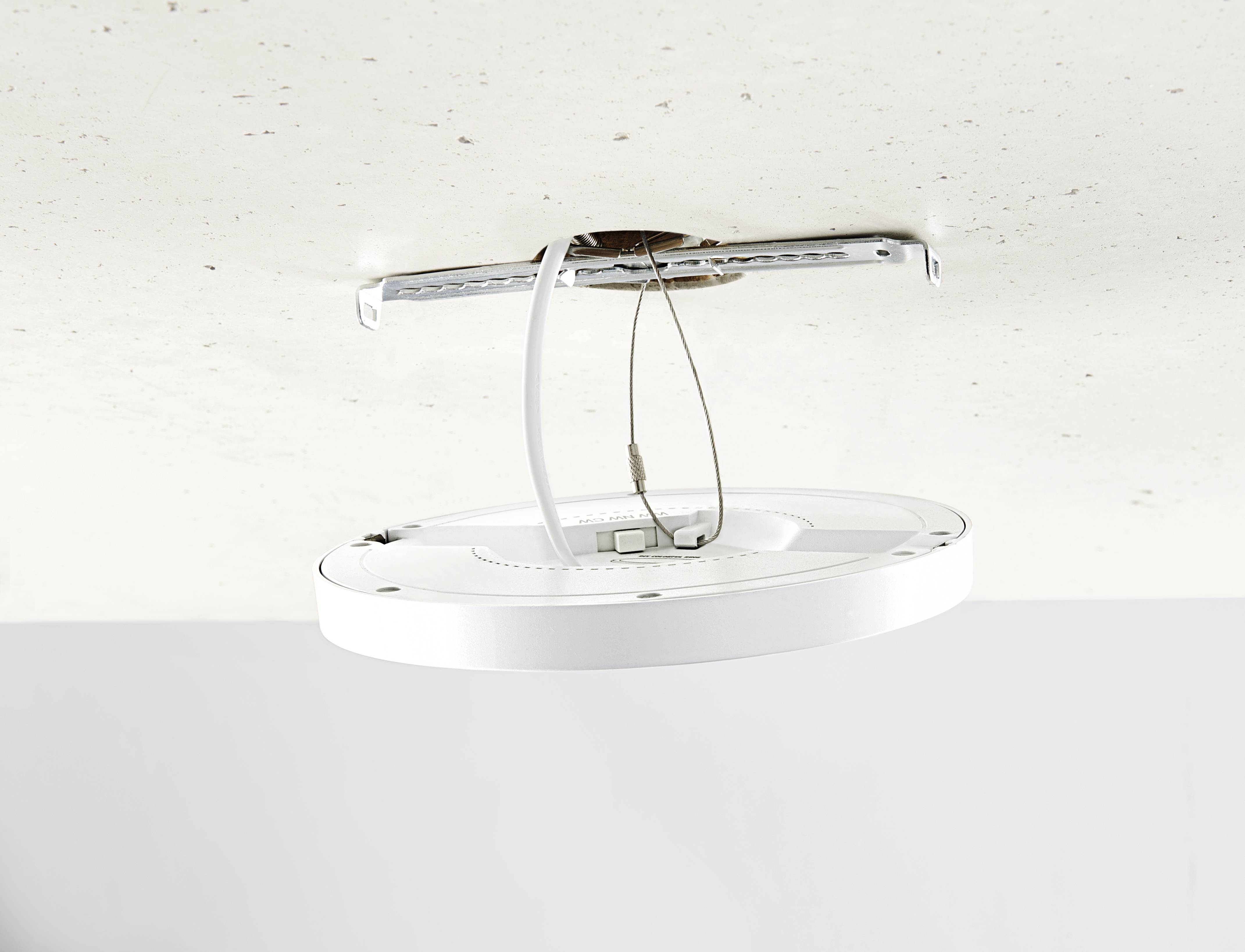 Eine runde, weiße LED-Deckenleuchte wird an einer weißen Decke montiert, mit sichtbaren Kabeln und Halterung im Aufbau.