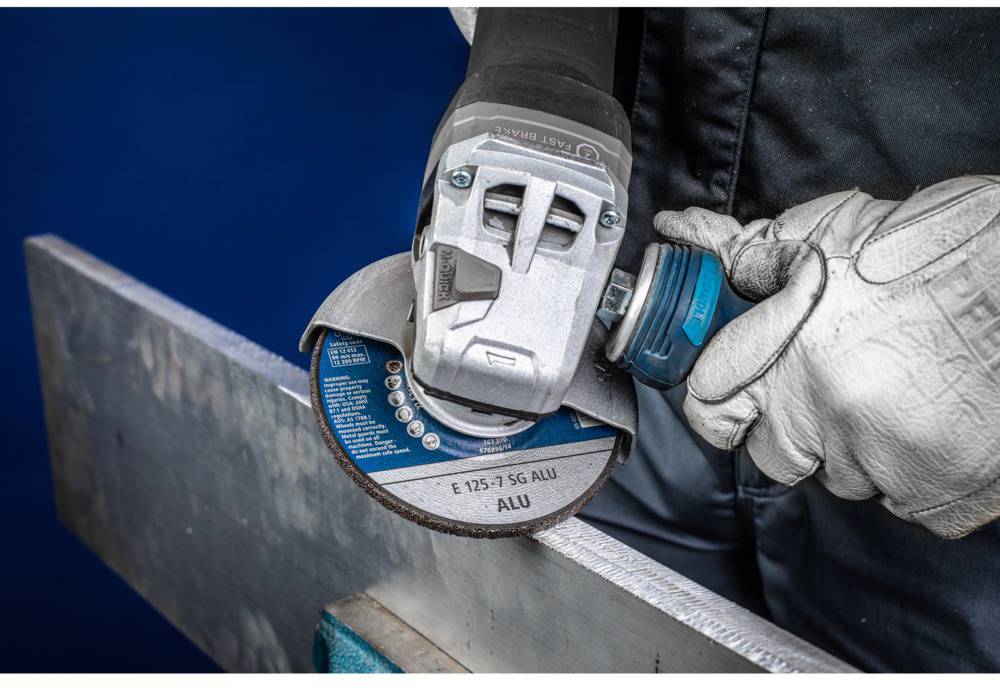 Eine Person bearbeitet mit einem Winkelschleifer ein Metallstück. Sie trägt Schutzhandschuhe, und die Funken fliegen vom Kontaktpunkt.