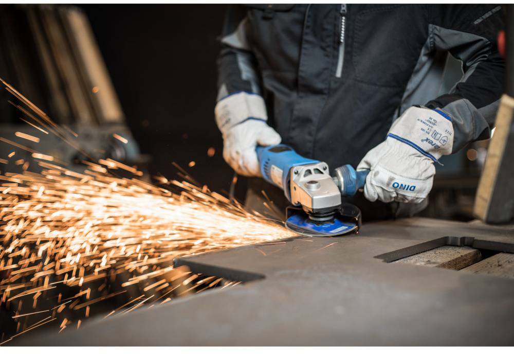 Eine Person schneidet Metall mit einem Winkelschleifer, während Funken sprühen. Die Szene zeigt handwerkliches Arbeiten im Detail.