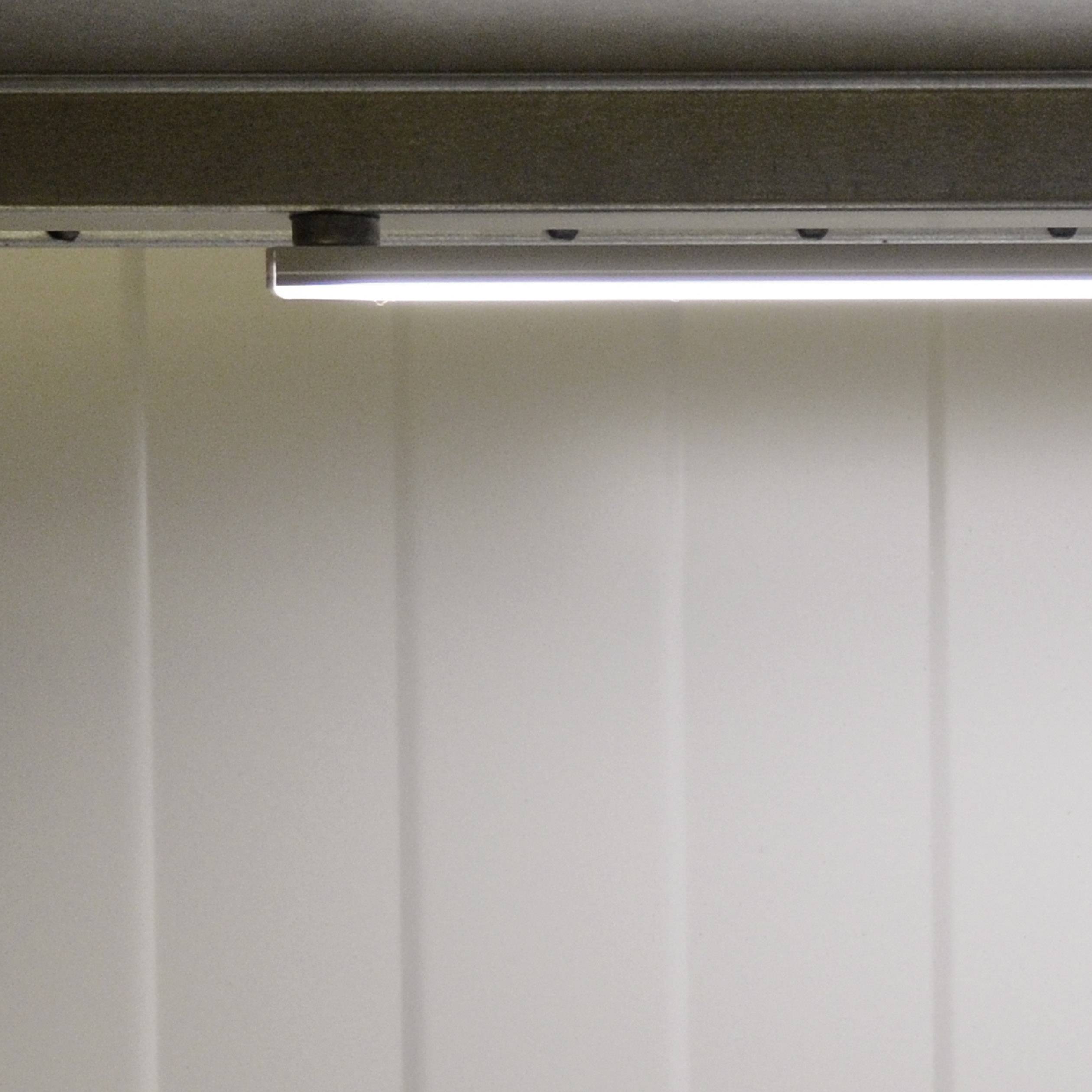 Ein langer, schmaler LED-Streifen strahlt helles Licht auf einer weißen, strukturierten Wand aus.